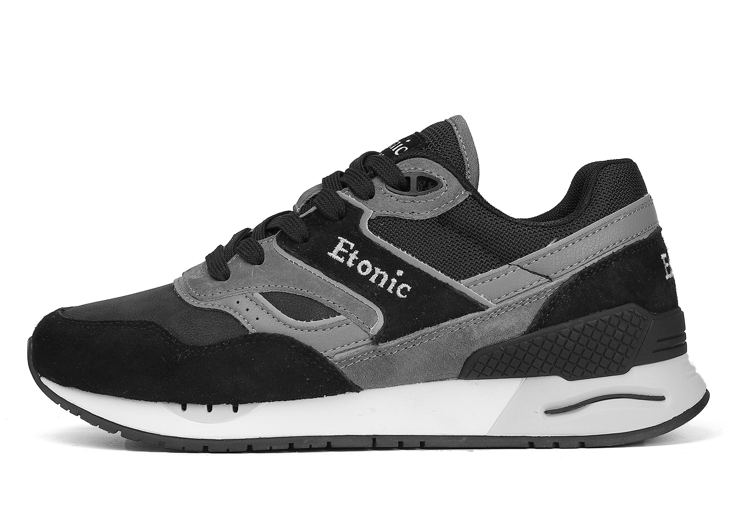 Sneakers Etonic Stable Base in nabuk nero, tessuto a rete tono su tono, pelle scamosciata nera con inserti in pelle multistrato grigio scuro, intersuola bianca e suola inferiore nera.