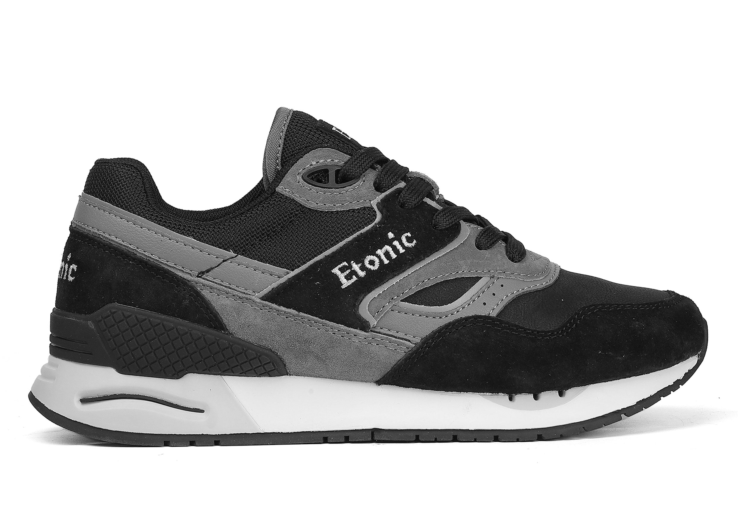 Sneakers Etonic Stable Base in nabuk nero, tessuto a rete tono su tono, pelle scamosciata nera con inserti in pelle multistrato grigio scuro, intersuola bianca e suola inferiore nera.