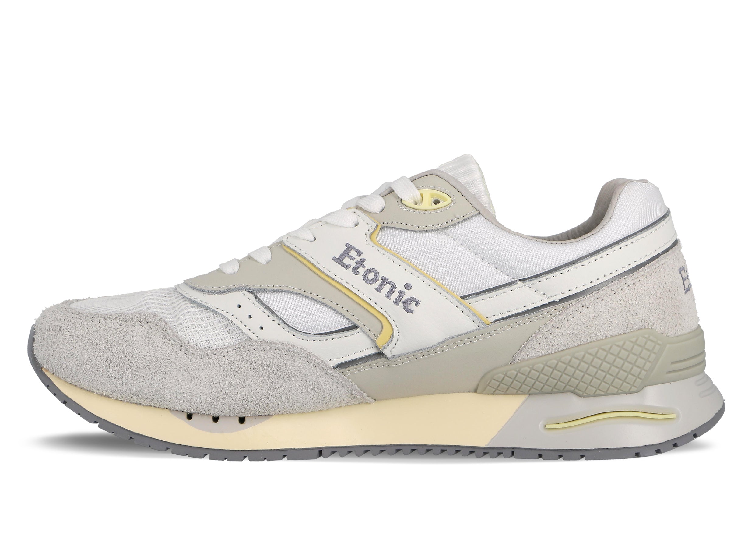 Sneakers Etonic Stable Base in tessuto a rete bianco, pelle scamosciata grigio ghiaccio con inserti in pelle bianca multistrato, dettagli grigio fumo e gialli, intersuola beige e suola inferiore grigio fumo.