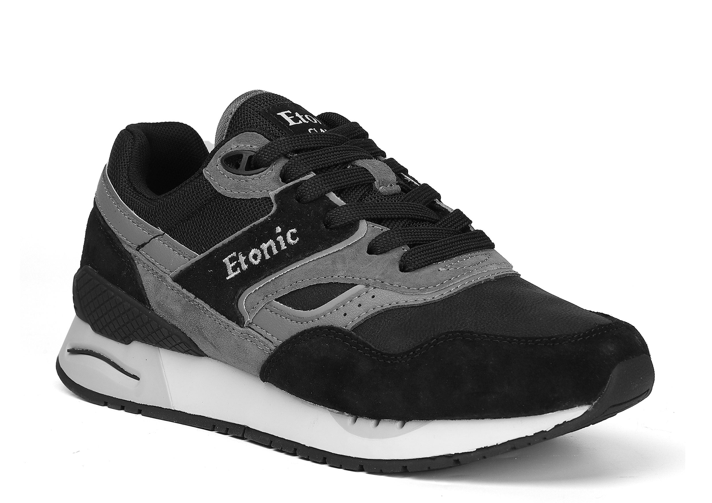 Sneakers Etonic Stable Base in nabuk nero, tessuto a rete tono su tono, pelle scamosciata nera con inserti in pelle multistrato grigio scuro, intersuola bianca e suola inferiore nera.